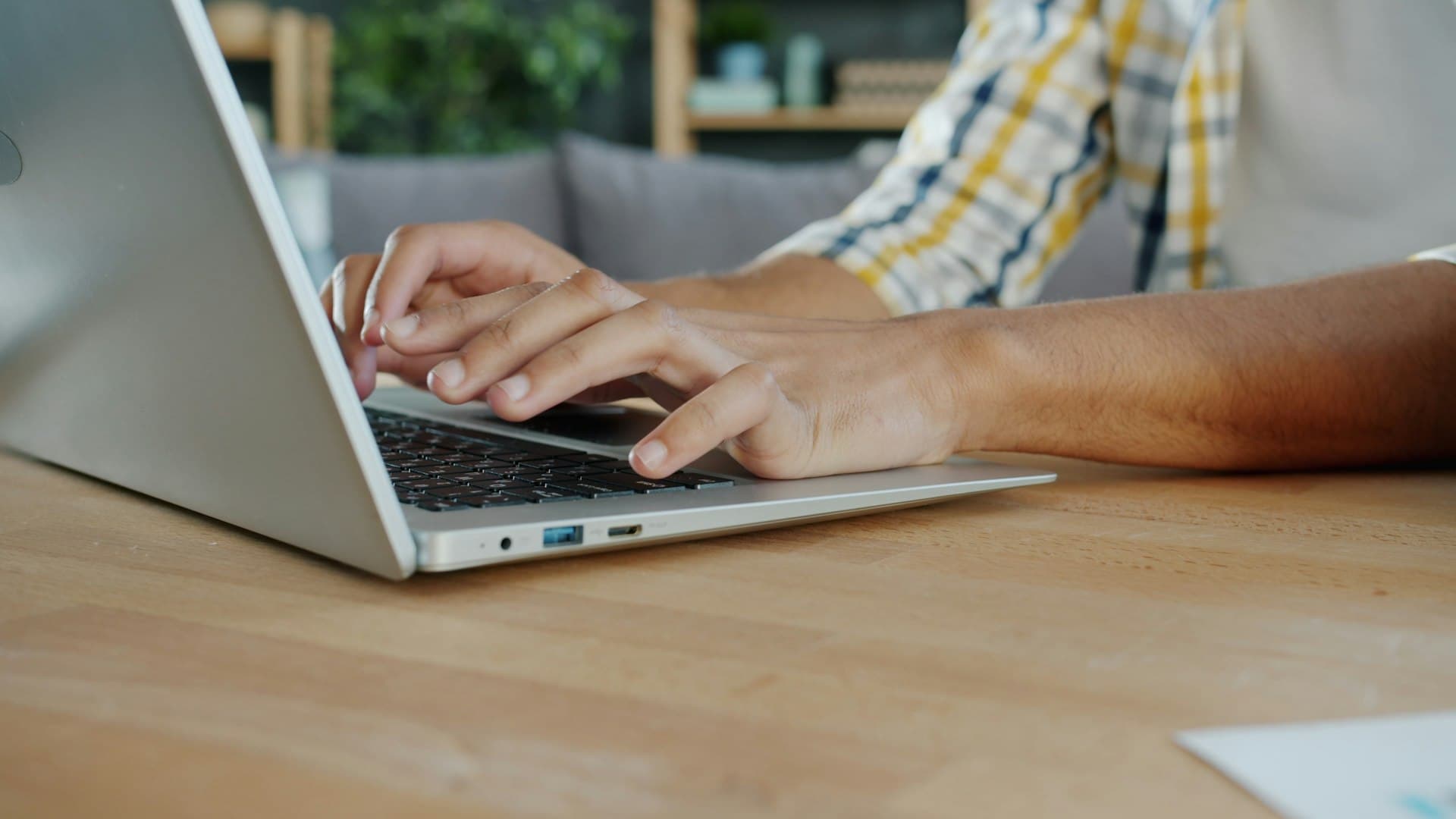 A staff member typing on a laptop at a wooden desk